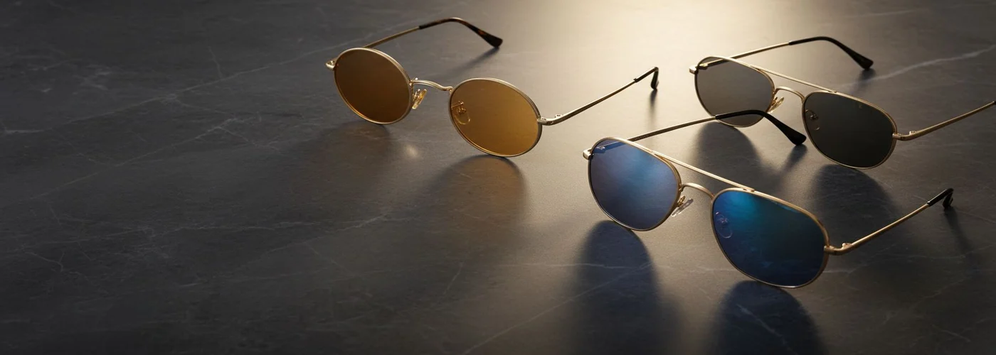 Several pairs of luxury sunglasses on polished dark stone.